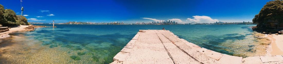 Panoramic view of pier at harbor against blue sky