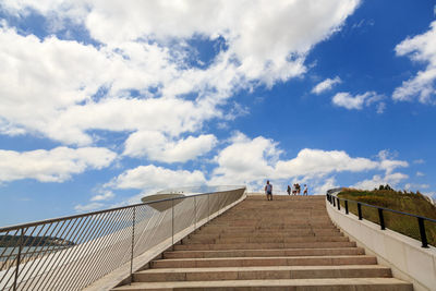 Low angle view of people on staircase against sky