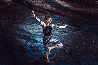 High angle view of woman with arms raised while standing in water