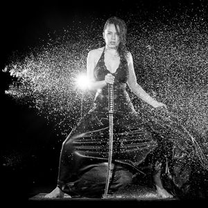 Portrait of young woman splashing against black background
