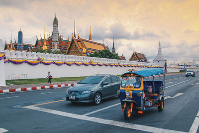 Vehicles on road against cloudy sky