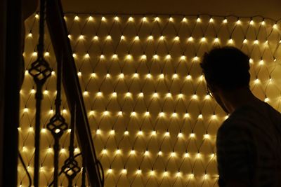 Rear view of man standing on illuminated light bulb