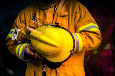 Midsection of firefighter holding helmet