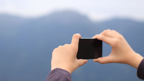 Close-up of woman photographing while using mobile phone