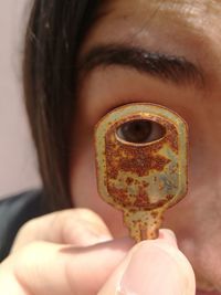Close-up portrait of woman looking through rusty key