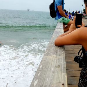 Low section of woman photographing on beach
