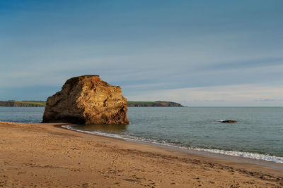 Rock formation on beach against sky