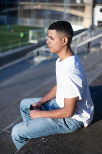 Side view of man sitting on street