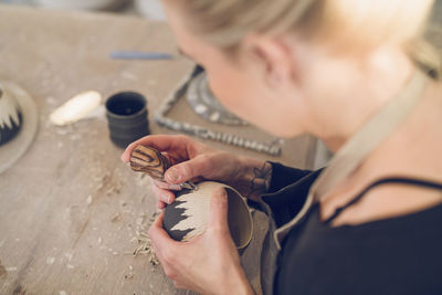 High angle view of woman carving ceramic at table in workshop