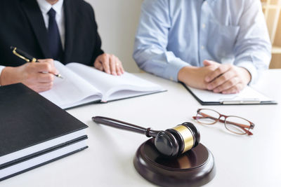 Midsection of man sitting by lawyer at table in courtroom