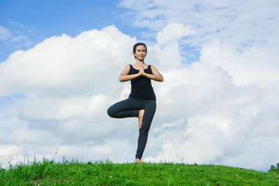 Full length of woman doing yoga against sky