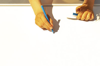 Close-up of woman holding hands over white background