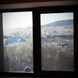 Scenic view of snow covered landscape seen through glass window