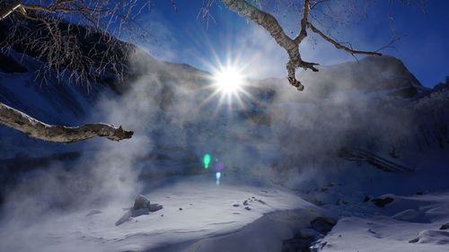 Sun shining through clouds over snow covered landscape