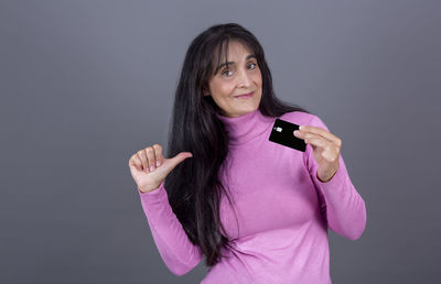 Portrait of young woman using mobile phone against gray background