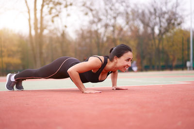 Full length of woman exercising at sports court