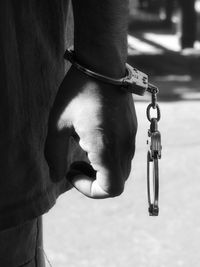 Close-up of hand holding chain hanging on metal