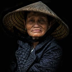 Portrait of woman wearing hat against black background