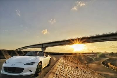 Cars on bridge against sky during sunset