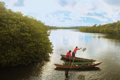 Men fishing in lake against sky