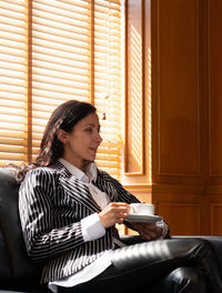 Young woman looking away while sitting in corridor