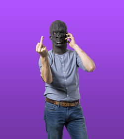 Full length of man standing against purple colored background