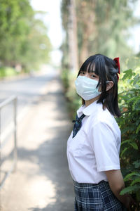 Portrait of young woman wearing mask standing outdoors