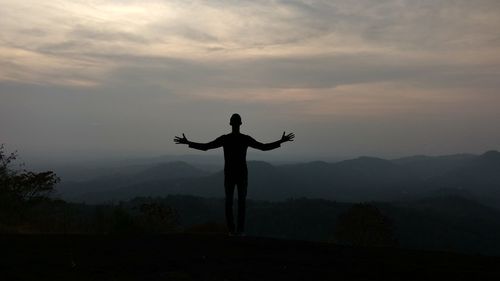 Silhouette man standing on mountain against sky during sunset