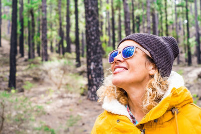 Woman wearing sunglasses in forest against trees