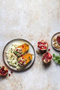Top view composition of plate with tasty rice and roasted pumpkin served with herbs and pomegranate near nuts