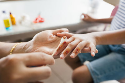 Parent helping her child perform first aid finger injury after she has been an accident.