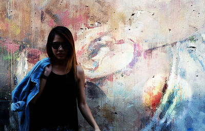 Portrait of young woman standing against wall