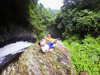 Young couple sitting on rock in forest