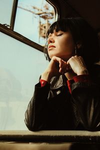 Girl looking away while sitting on window