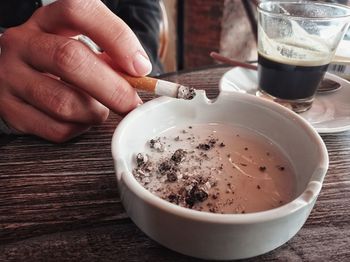 Close-up of hand holding drink on table