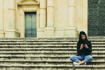 Full length of woman sitting on staircase