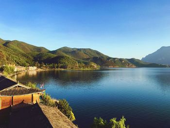 Scenic view of lake and mountains against clear blue sky