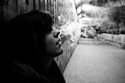 Woman smoking by wall