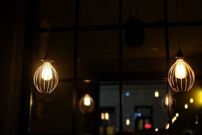 Low angle view of illuminated light bulbs against window