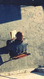 High angle view of man reading novel at building terrace