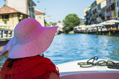 Rear view of woman with hat on boat in water