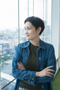 Smiling woman with arms crossed looking through window