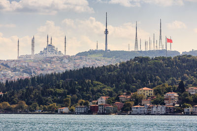 Buildings at waterfront against cloudy sky