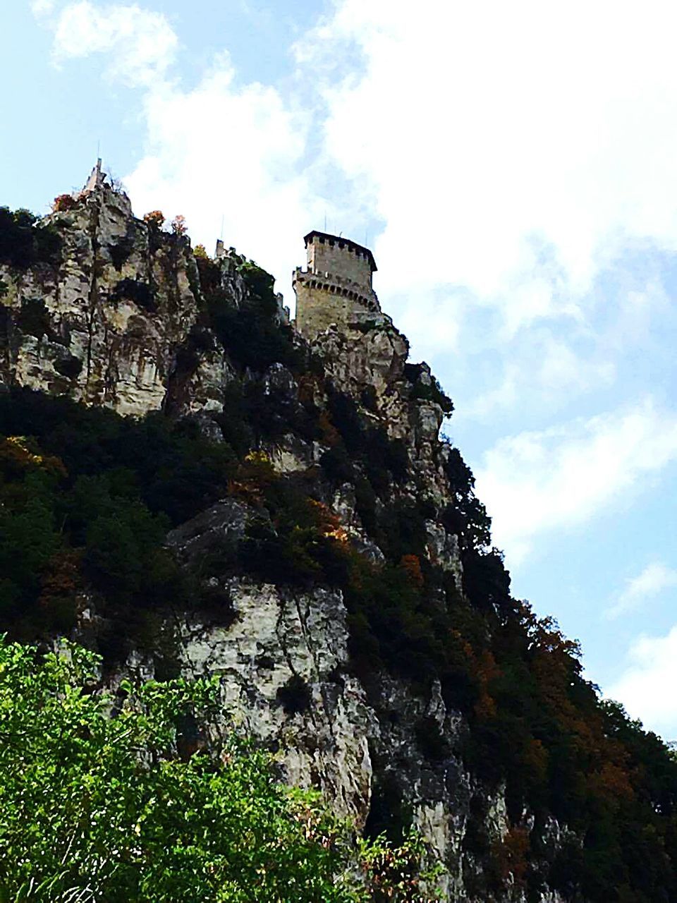 sky, cloud - sky, day, low angle view, rock - object, history, travel destinations, outdoors, mountain, architecture, nature, no people, built structure, cliff, scenics, building exterior, beauty in nature, tree, ancient civilization