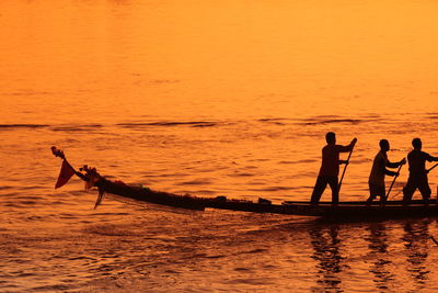 Silhouette fisherman on boats at sea during sunset