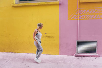 Full length of woman standing against wall