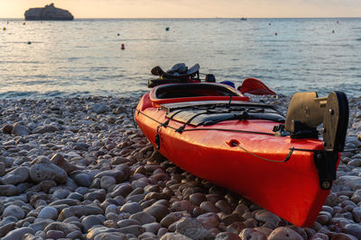 Pebbled beach with empty kayaks at sunrise.