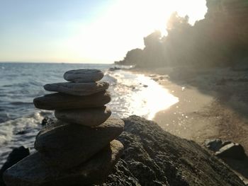 Stack of pebbles on beach against sky during sunset