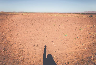 Shadow of person on landscape against sky