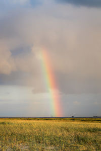 Scenic view of rainbow over field against sky